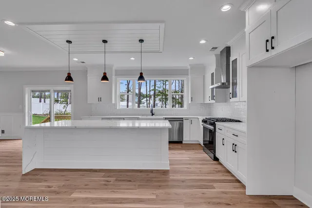 a large kitchen with stainless steel appliances a large counter top a stove a sink dishwasher and a refrigerator