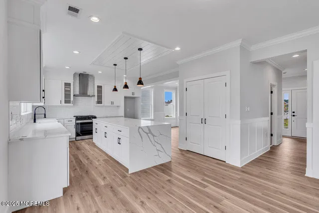 a large white kitchen with wooden floors and stainless steel appliances
