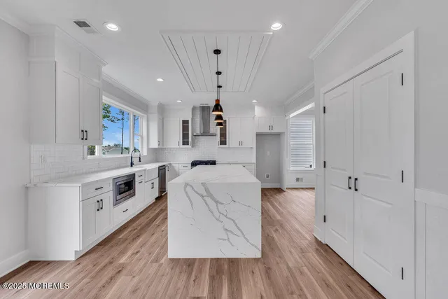 a large white kitchen with a large window a cabinetry and stainless steel appliances