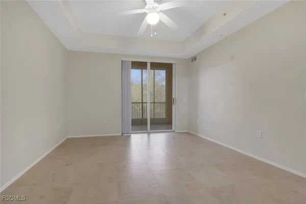 an empty room with chandelier fan and windows