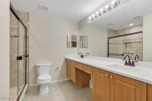 a bathroom with a toilet sink double vanity and mirror