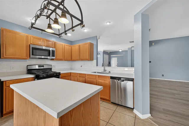 a kitchen with stainless steel appliances granite countertop a sink a stove top oven a counter space and cabinets