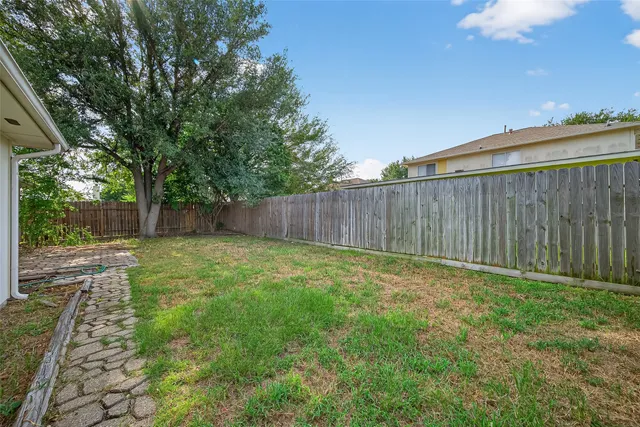 a view of a backyard with large trees and wooden fence