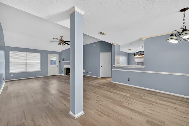 a view of an empty room with window and wooden floor