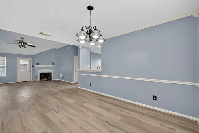 a view of a livingroom with a fireplace a chandelier and wooden floor
