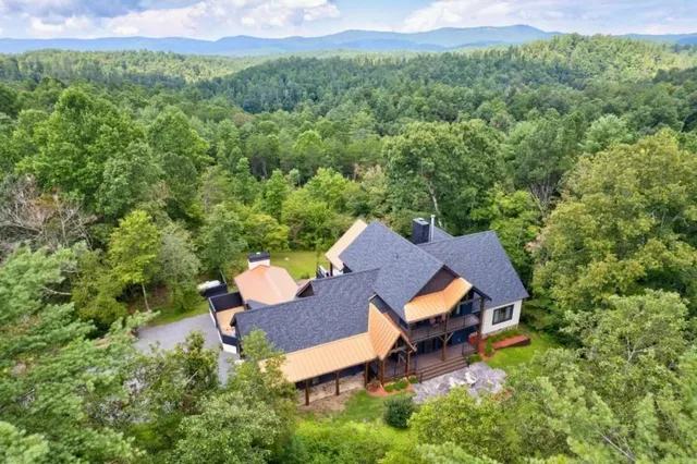 a view of a house with a big yard and large trees