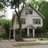 a view of a white house with a small yard and large tree