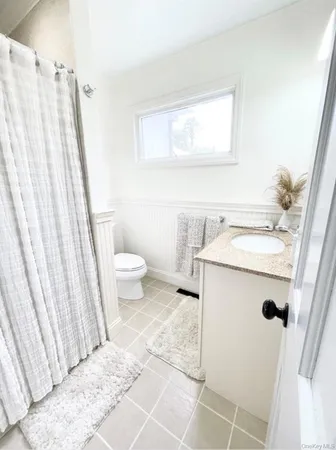 a bathroom with a sink a toilet a mirror and shower curtain