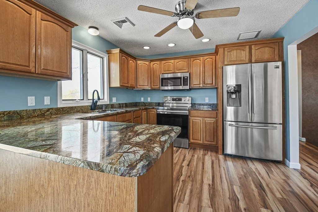 5 Jackson Road Webster, MA 01570 - Photo 5 of 30 a kitchen with stainless steel appliances granite countertop a refrigerator a stove top oven a sink dishwasher and wooden cabinets