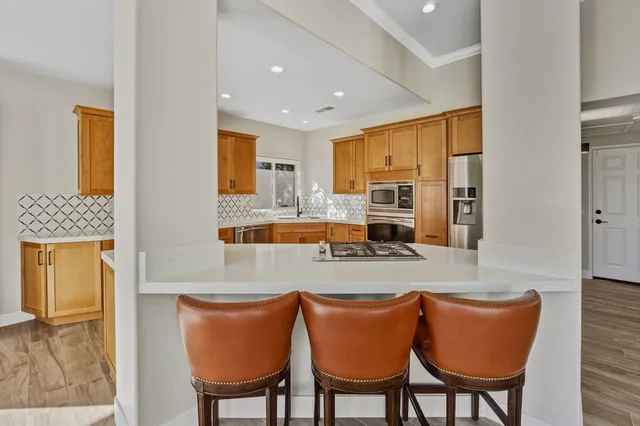 a kitchen with stainless steel appliances granite countertop a dining table chairs and a refrigerator