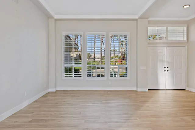 a view of an empty room with wooden floor and a window