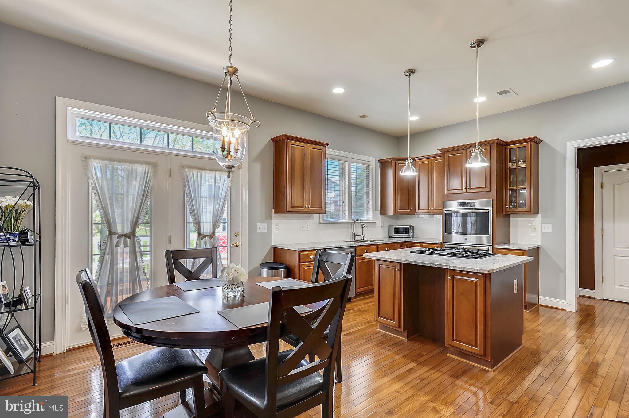 4855 Muddler Way Fairfax, VA 22030 - Photo 11 of 30 a kitchen with granite countertop kitchen island stainless steel appliances a dining table chairs sink and wooden floor