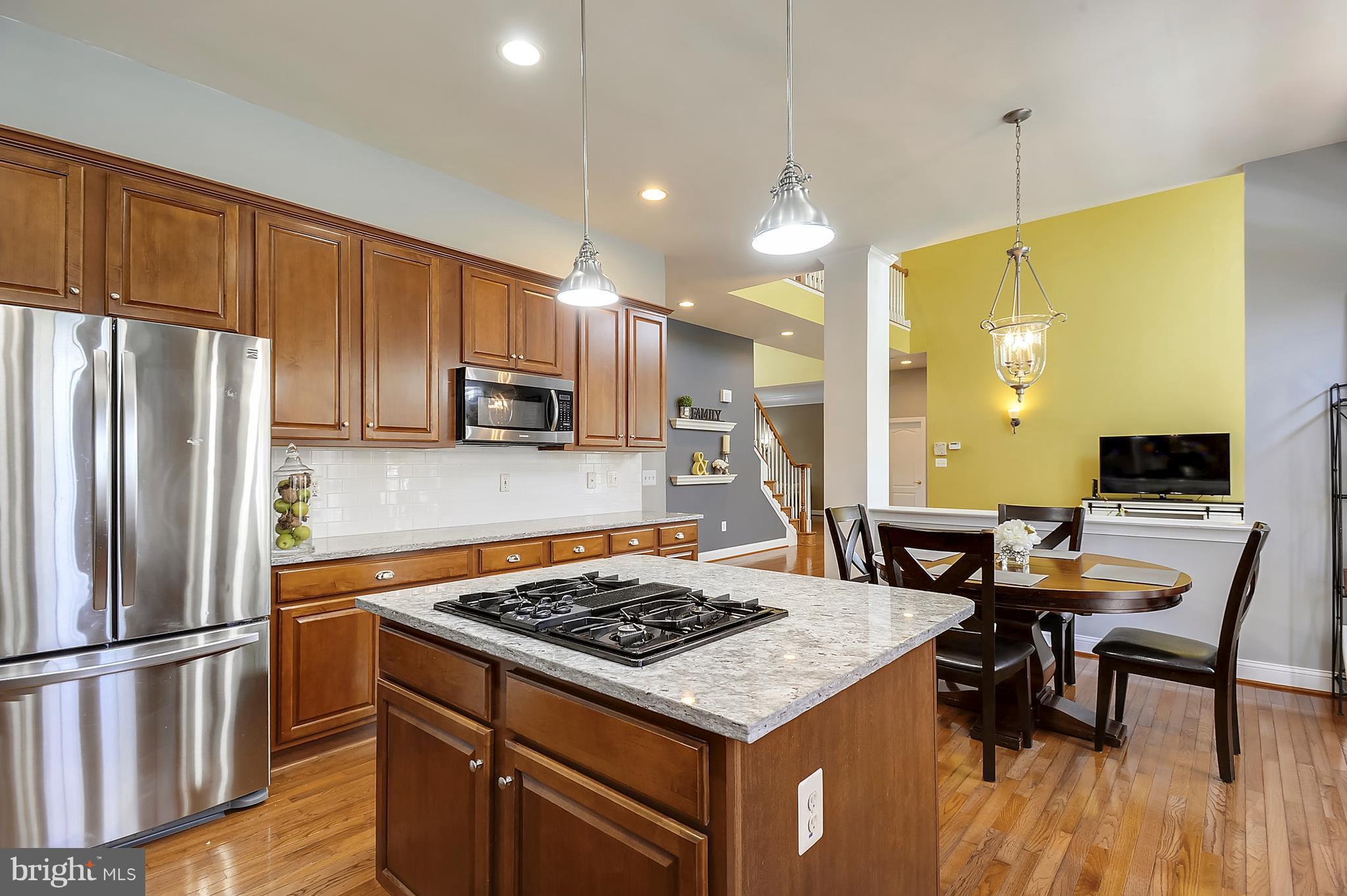 4855 Muddler Way Fairfax, VA 22030 - Photo 12 of 30 a kitchen with a stove a refrigerator and a dining table with wooden floor