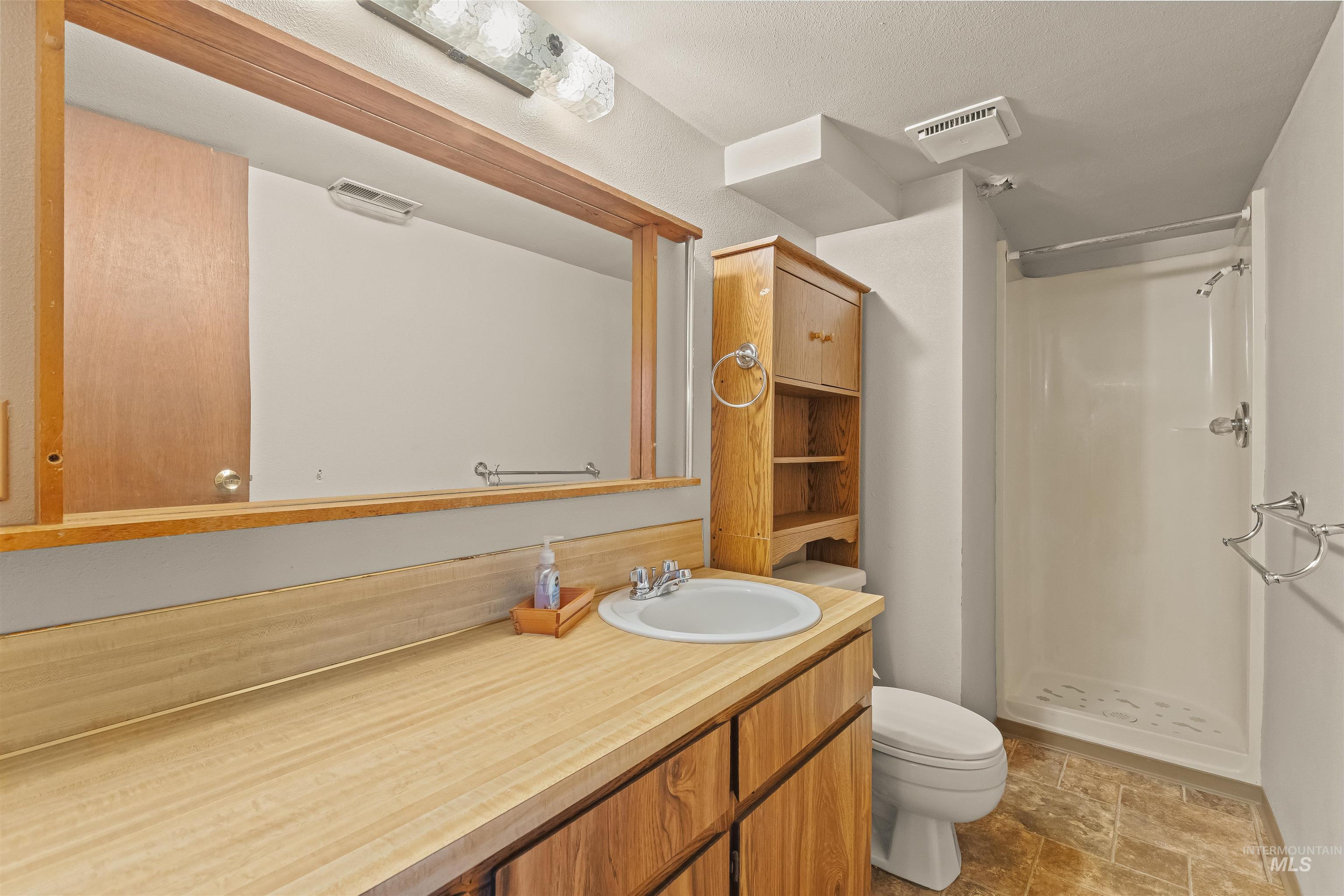 1663 9th Avenue Lewiston, ID 83501 - Photo 16 of 36 Bathroom featuring a wood-finish vanity with an integrated sink, a large framed mirror, and a shower stall with chrome fixtures