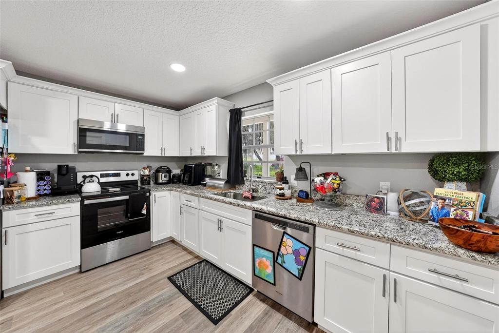 106 Portland Street Eustis, FL 32726 - Photo 26 of 71 a kitchen with stainless steel appliances granite countertop a stove a sink dishwasher and a refrigerator with white cabinets