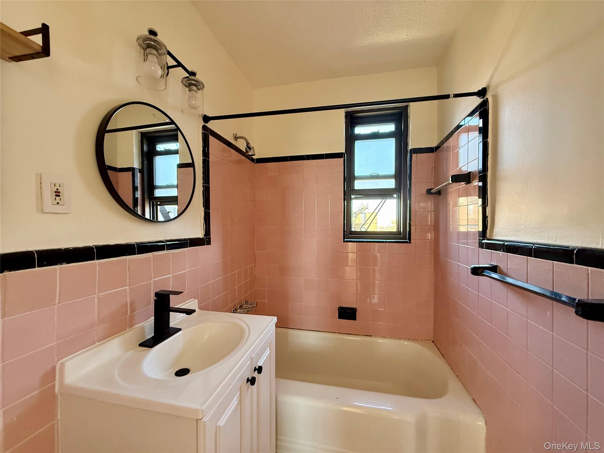 112-25 34th Avenue, Unit 6H Queens, NY 11368 - Photo 19 of 48 Original bathroom with updated sink, lights and mirror. Window for ventilation, tile on the floors and walls.