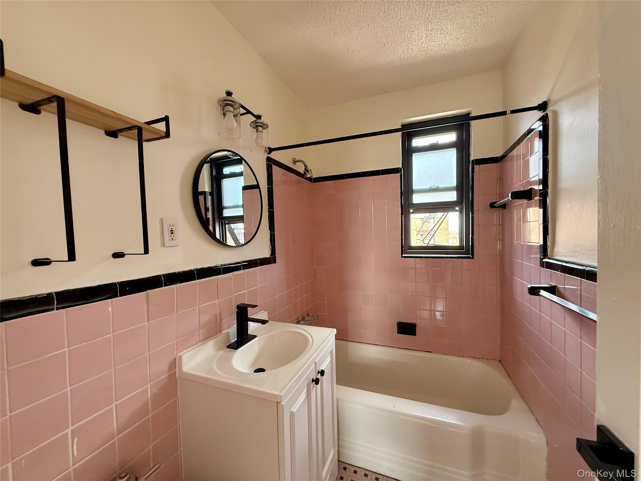 112-25 34th Avenue, Unit 6H Queens, NY 11368 - Photo 20 of 48 Original bathroom with updated sink, lights and mirror. Window for ventilation, tile on the floors and walls.