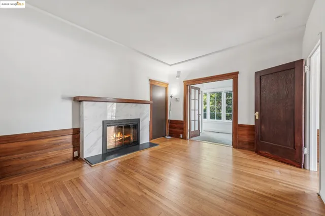 a view of an empty room with wooden floor fireplace and a window