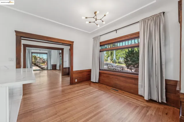 a view of an empty room with window wooden floor and a kitchen