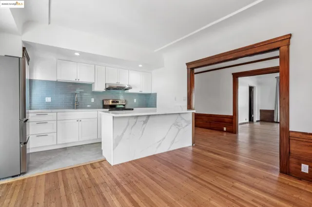 a kitchen with wooden floors and white cabinets