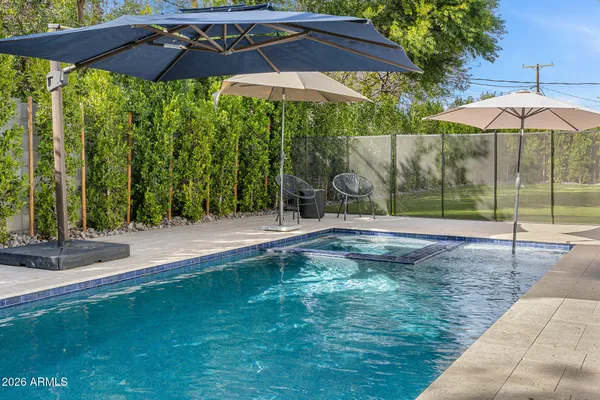 a backyard of a house with table and chairs under an umbrella