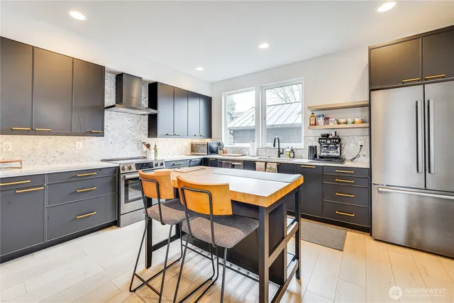 a kitchen with stainless steel appliances granite countertop a refrigerator a sink dishwasher a stove and white countertops with wooden floor