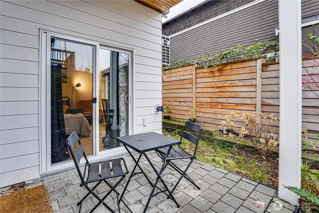 a patio with table and chairs and potted plants