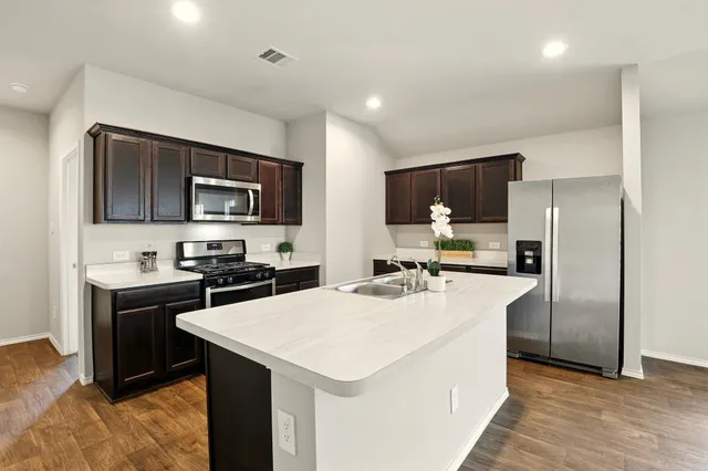 a kitchen with a sink a counter top space appliances and cabinets