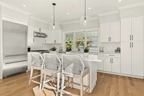 a kitchen with stainless steel appliances kitchen island granite countertop a table chairs refrigerator and microwave