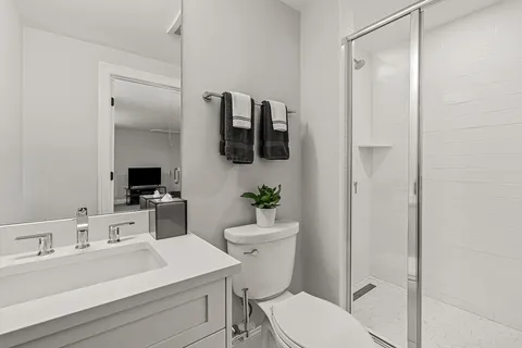 a bathroom with a sink a toilet a mirror and shower
