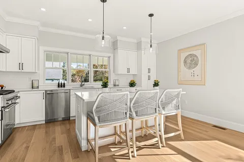 a kitchen with stainless steel appliances granite countertop a sink a stove a refrigerator and island with wooden floor