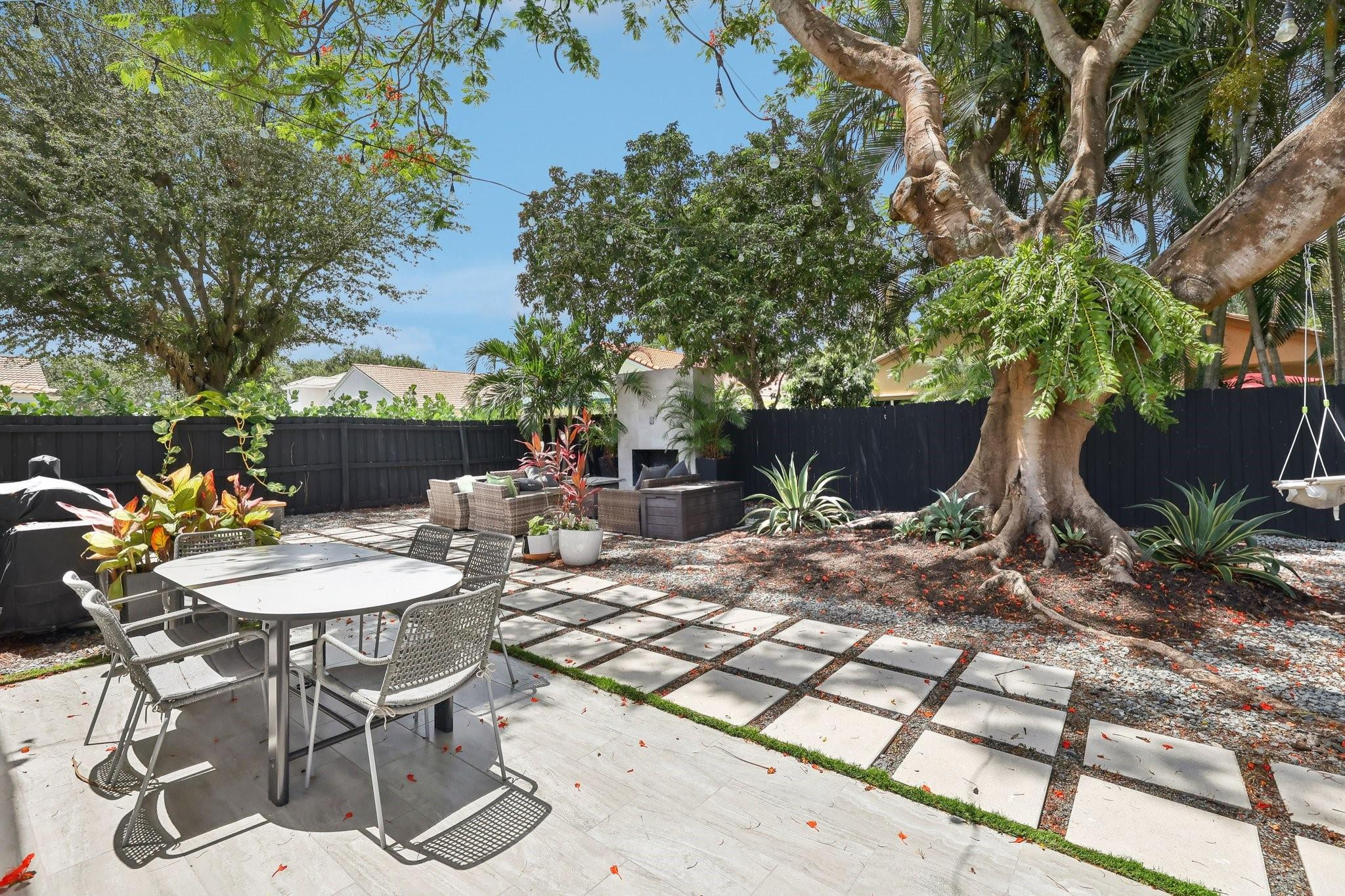 4035 Sabal Lakes Road Delray Beach, FL 33445 - Photo 31 of 43 a view of a backyard with table and chairs potted plants and a large tree