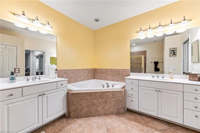 a spacious bathroom with a double vanity sink mirror and bathtub