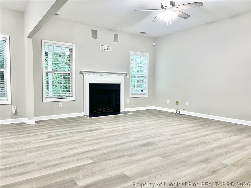 1523 Rough Rider Lane Parkton, NC 28371 - Photo 12 of 42 an empty room with wooden floor fireplace and windows