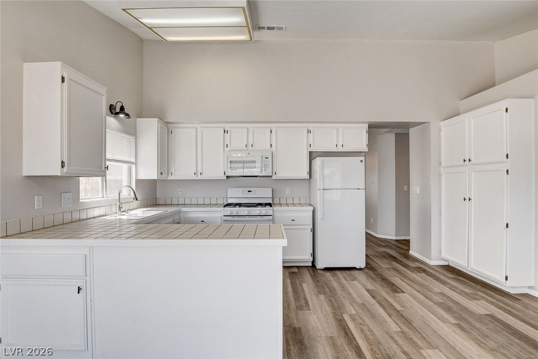 6209 Warm River Road Las Vegas, NV 89108 - Photo 19 of 39 A well-lit kitchen with soaring ceilings and ample white cabinetry for storage.