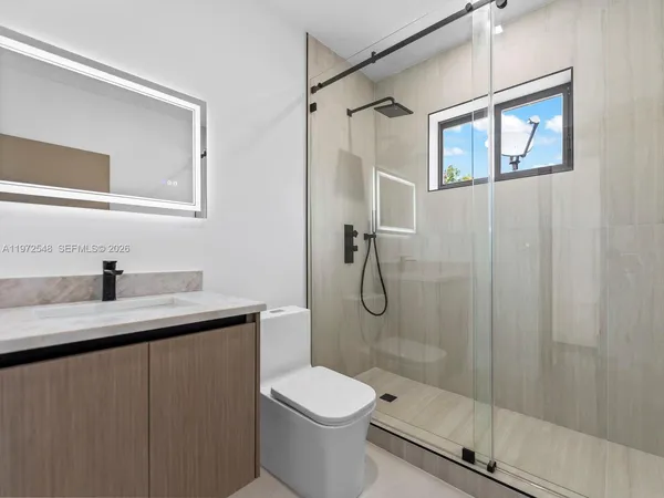 a bathroom with a granite countertop sink toilet and shower