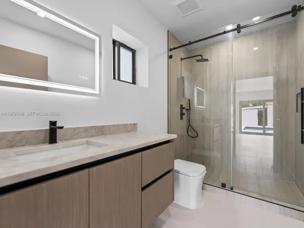 a bathroom with a granite countertop sink a toilet and shower