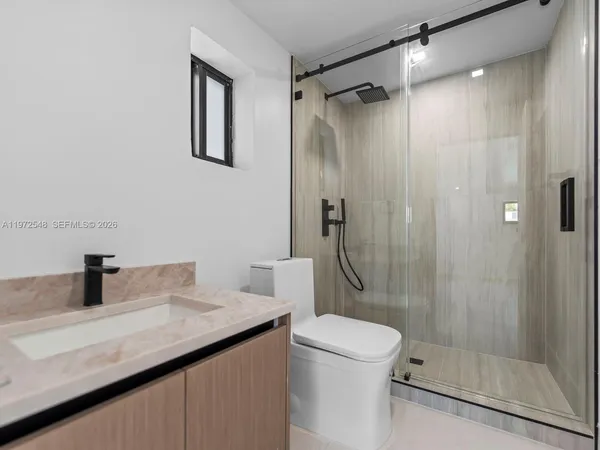 a bathroom with a granite countertop sink a toilet and shower