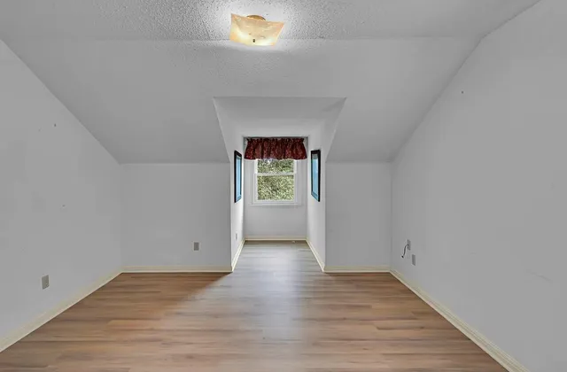 a view of a room that has wooden floor and a window
