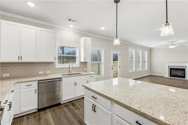 a large kitchen with granite countertop a sink a counter space appliances and cabinets