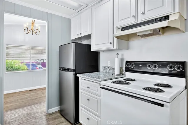 a kitchen with stainless steel appliances granite countertop a refrigerator stove and white cabinets