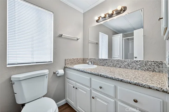 a bathroom with a granite countertop toilet sink and mirror