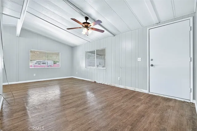 an empty room with wooden floor ceiling fan and windows