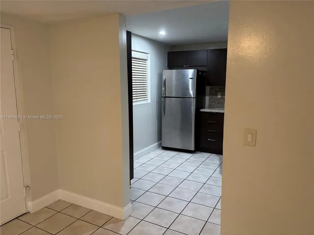 a view of a refrigerator in kitchen and an empty room