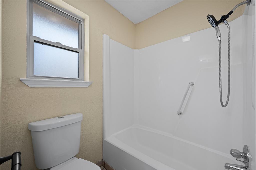 1102 Lena Street Cleburne, TX 76033 - Photo 21 of 36 a bathroom with a granite countertop toilet a sink and bathtub