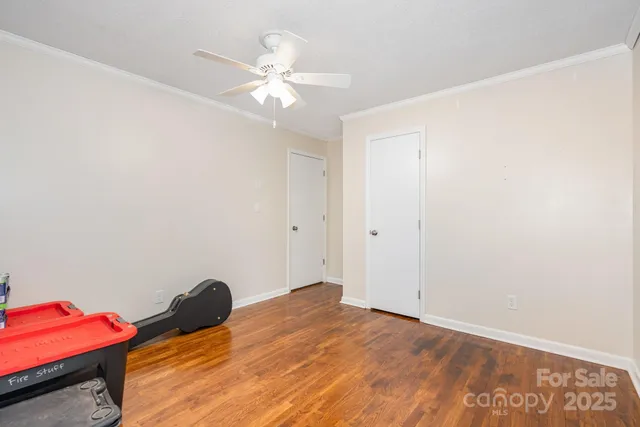 an empty room with wooden floor fan and windows