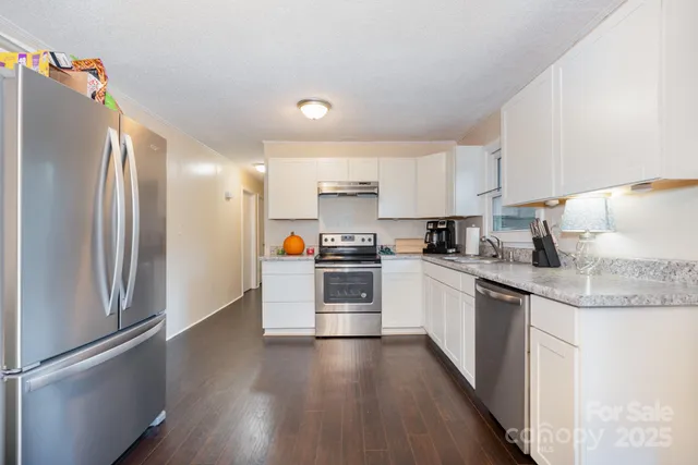 a kitchen with stainless steel appliances granite countertop a refrigerator a stove and a sink