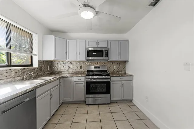 a kitchen with stainless steel appliances granite countertop a stove top oven a sink and a refrigerator