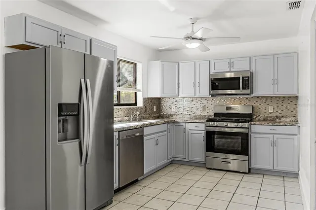 a kitchen with stainless steel appliances granite countertop a stove a refrigerator and a microwave