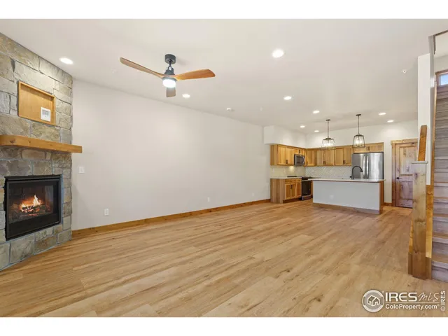 a view of kitchen and empty room with wooden floor